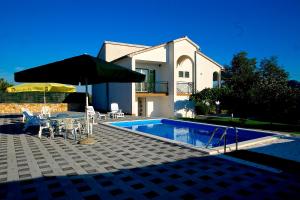 ein Haus mit einem Pool, einem Tisch und einem Sonnenschirm in der Unterkunft Holiday Home Vinac in Dazlina