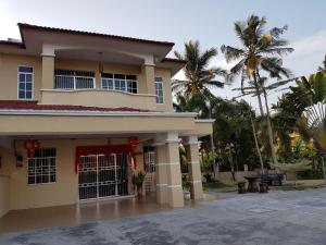 een groot huis met palmbomen op de achtergrond bij Big Garden Homestay in Pantai Remis