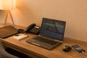 a laptop computer sitting on a desk with a phone at Hotel cooju Fukui in Sakai