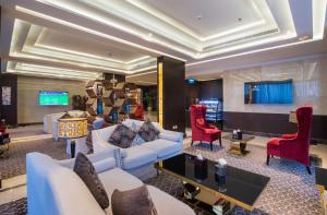 a living room with white furniture and red chairs at Mayan for service apartments in Riyadh