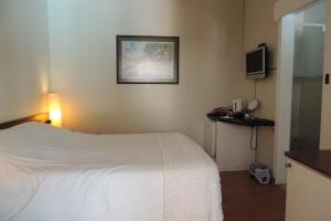 a hotel room with a white bed and a television at Brackens Guest House in Hillcrest