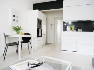 ヘルシンキにあるRoost Kristianの白いキャビネット、テーブルと椅子付きのキッチンが備わります。