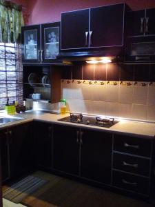 a kitchen with black cabinets and a stove top oven at Idaman Sinar Homestay in Nibung Tebal