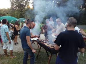a group of people standing around a barbecue grill at Camping Au Bois Dormant in Chauffour-sur-Vell