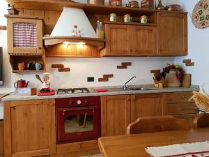 cocina con armarios de madera y horno rojo en Casa Vacanze Corteno Golgi Aprica, en Alpe Strencia