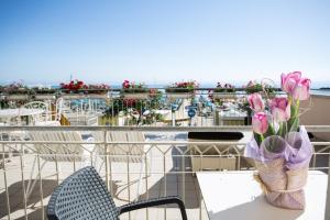 - une table avec un vase de fleurs sur le balcon dans l'établissement Hotel Lido, à Bellaria-Igea Marina
