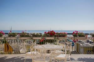 une terrasse avec des chaises, une table et des fleurs dans l'établissement Hotel Lido, à Bellaria-Igea Marina