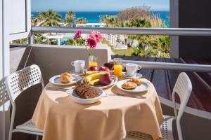 uma mesa com comida para o pequeno almoço numa varanda com o oceano em Dorian Boutique Hotel-Apartments em Hersonissos