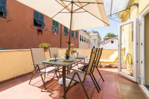 einen Tisch mit Stühlen und einem Sonnenschirm auf dem Balkon in der Unterkunft Apartment In The Heart Of Sanremo in Sanremo