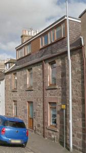 a blue car parked in front of a brick building at Rooms at 31 in Stonehaven