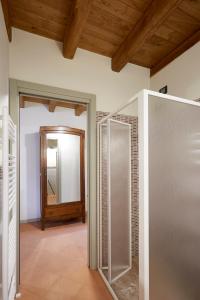 uma casa de banho com uma cabina de duche ao nível do chão e um espelho. em Palazzo Eleonora em Monasterolo del Castello