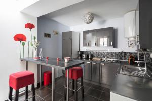 une cuisine avec tabourets rouges et comptoir noir dans l'établissement L'Atelier Nantais by Cocoonr, à Nantes