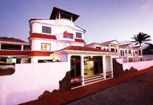 a large white building with a palm tree behind it at Arena Blanca Eco Hotel in Puerto Baquerizo Moreno