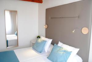 a bedroom with a bed with blue and white pillows at TRH Tirant Playa in Fornells