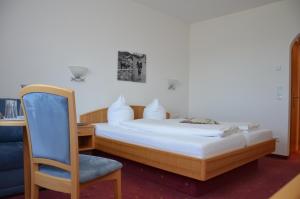 a bedroom with a bed with a chair and a desk at Gasthof Hirschen in Sibratsgfäll