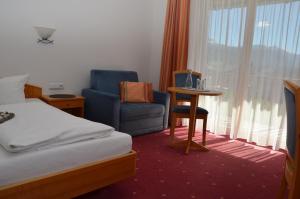 a hotel room with a bed and a chair and a window at Gasthof Hirschen in Sibratsgfäll