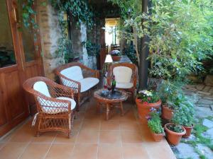 un patio con sillas de mimbre, mesas y plantas en La Casa del Filandón- HOTEL RURAL, en Quintanilla de Somoza