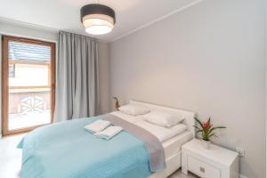 a white bedroom with a bed and a window at Apartamenty Pod Gubałówką in Zakopane
