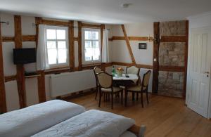 a bedroom with a table and chairs and a bed at Hotel & Café Mohrenbrunnen in Eisenberg