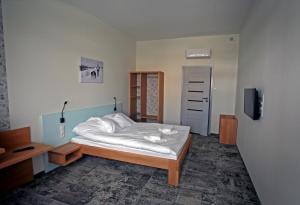 a bedroom with a white bed and a tv at Motelik Grosar Gorlice in Gorlice