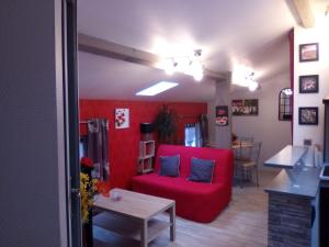 a living room with a red couch and a table at Les Ponts de l'Ornain in Bar-le-Duc