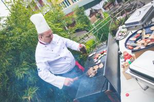 a chef is cooking food on a grill at Therma Nea Dunajská Streda in Dunajská Streda