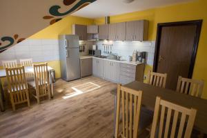 a kitchen with a table and chairs and a refrigerator at Camere de închiriat Hătuica in Hătuica
