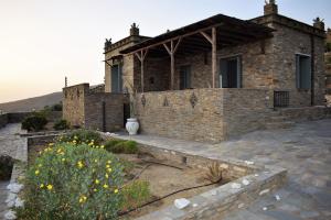een groot bakstenen huis met een tuin ervoor bij Sunrise Stone Residence in Ándros