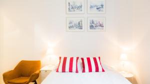 a bed with a red and white striped pillow and a chair at Vironkatu 3 in Helsinki