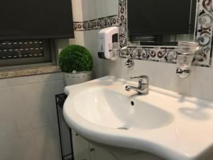 a bathroom with a white sink and a mirror at Real Caparica Hotel in Costa da Caparica