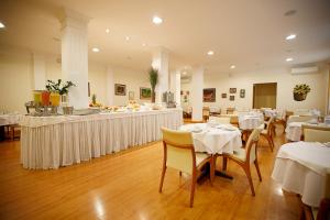 um restaurante com mesas e cadeiras brancas e um bar em Eston Hotel - LOCALIZAÇÃO CENTRAL PRIVILEGIADA -PET FRIENDLY em Chapecó