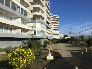 un gran edificio de apartamentos con flores delante en El Faro Premium Frente al Mar, en La Serena