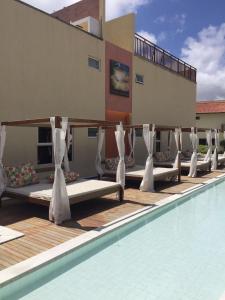 a row of beds on the side of a swimming pool at Solar Água - Apto. 114 in Pipa