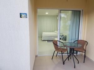 a table and chairs in a room with a bedroom at Solar Água - Apto. 114 in Pipa