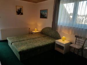 a bedroom with a bed and a window and a chair at Apart-Bungalovy Gitka in Mlynčeky