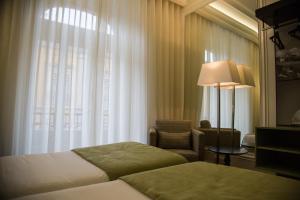 a hotel room with two beds and a chair and a window at Hotel Dublin in Lisbon