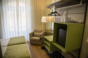 um quarto de hotel com uma cama, uma televisão e uma cadeira em Hotel Dublin em Lisboa