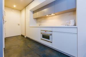 cocina con armarios blancos y suelo de baldosa en Zigzak Apartments Superior 9A, en Rzeszów