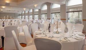 a large room with white tables and white chairs at Glasgow Grosvenor Hotel in Glasgow