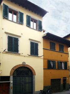 un edificio amarillo con ventanas con contraventanas verdes y garaje en Macci, en Florencia