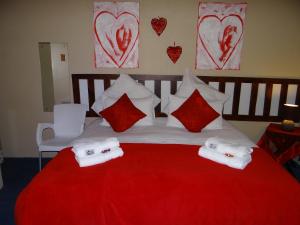 Una cama roja y blanca con toallas. en Obrigado Guest House, en De Aar
