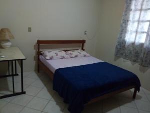 Dormitorio pequeño con cama y mesa en Casas na Praia de Bombas - Bombinhas, en Bombinhas