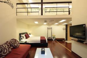 a bedroom with a bed and a couch and a tv at Happiness Yes Hostel 2 in Luodong