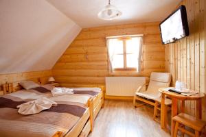 a bedroom with two beds and a tv on the wall at Penzión Koliba in Dolný Kubín