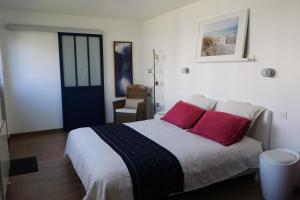 a bedroom with a bed with two red pillows at Le cabanon in La Rochelle