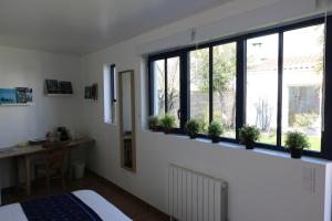 a bedroom with windows and potted plants on a ledge at Le cabanon in La Rochelle