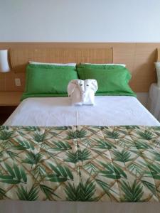 two stuffed animals sitting on a bed with green pillows at Beach Class Slin Muro Alto in Porto De Galinhas +23 photos