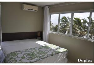a bedroom with a bed and a window with a palm tree at Costa Brava Praia Hotel in Lucena +27 photos