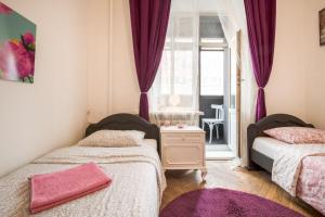 モスクワにあるLuxury Art Apartmentの紫色のカーテンと窓が備わる客室のベッド2台