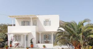 une maison blanche avec un palmier devant dans l'établissement George's Place Sifnos - apartments, à Apollonia
